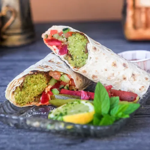 Deluxe Falafel Sandwich - Served with hummus, tomato, lettuce, eggplant, pickles, tahini sauce and shatta sauce.